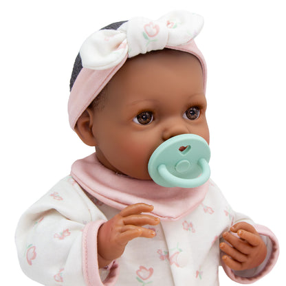 Baby doll with a pacifier wearing a headband and outfit on a white background
