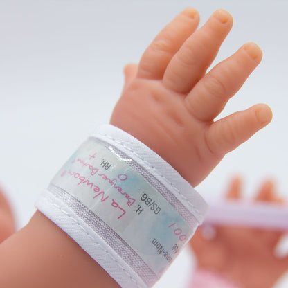 Close-up of a baby's hand wearing a hospital wristband with text on a blurred background