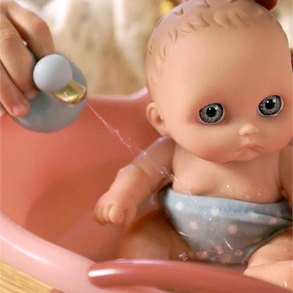 Lil' Cutesies twin baby doll in a pink bathtub, being showered by a blue duck toy.
