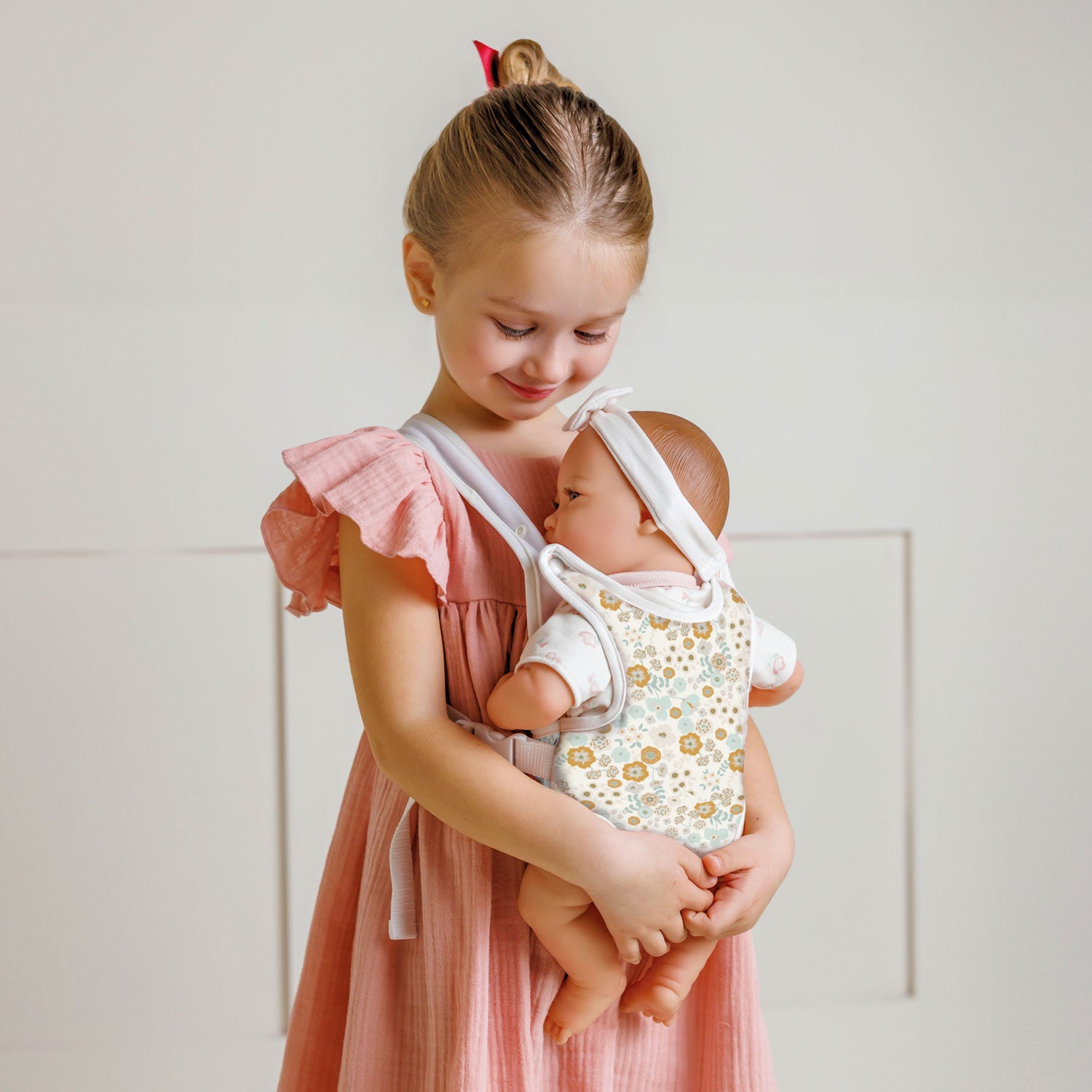 Young girl holding a baby doll against a light background
