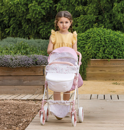 Young girl in a yellow dress pushing a pink stroller outdoors.