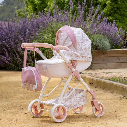 Pink and white floral pram with matching bag in a garden setting