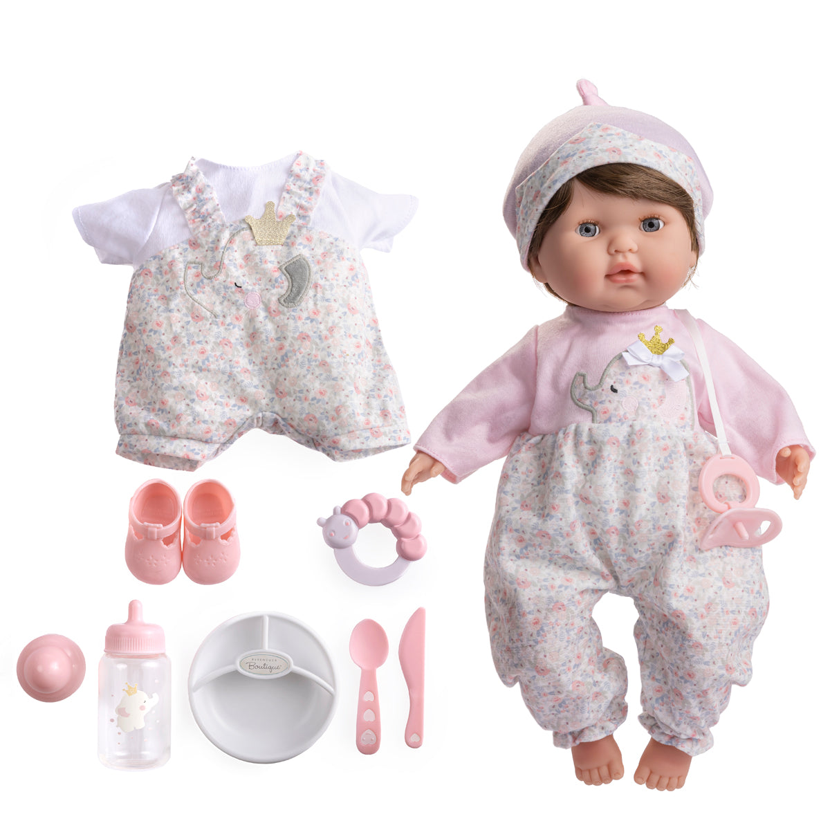 A realistic soft body baby doll with brown hair and open/close eyes, dressed in a pink outfit, accompanied by a two-piece embroidered outfit, shoes, a baby bottle, pacifier, rattle, and feeding accessories.