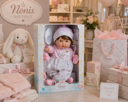 Baby doll in a box with 'Nonis Boutique' branding, surrounded by toys and gift bags.