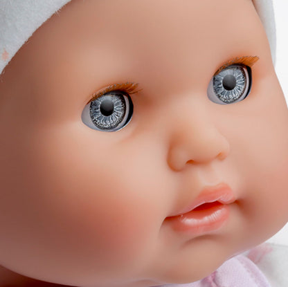 Close-up of a realistic baby doll's face with blue eyes, light skin, and a pink outfit.
