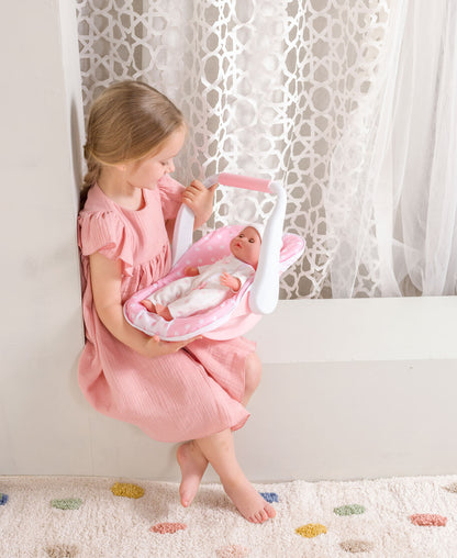 Girl in pink dress holding a 12.5" baby doll in a pink polka dot carrier.