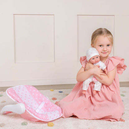 Young girl in pink dress holding a 12.5" baby doll, with a pink polka dot carrier beside her.