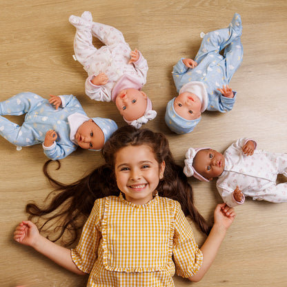 Young girl lying on a wooden floor with four baby dolls around her.