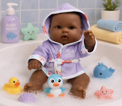 Baby doll in a bathrobe sitting in a bathtub with bath toys and soap.